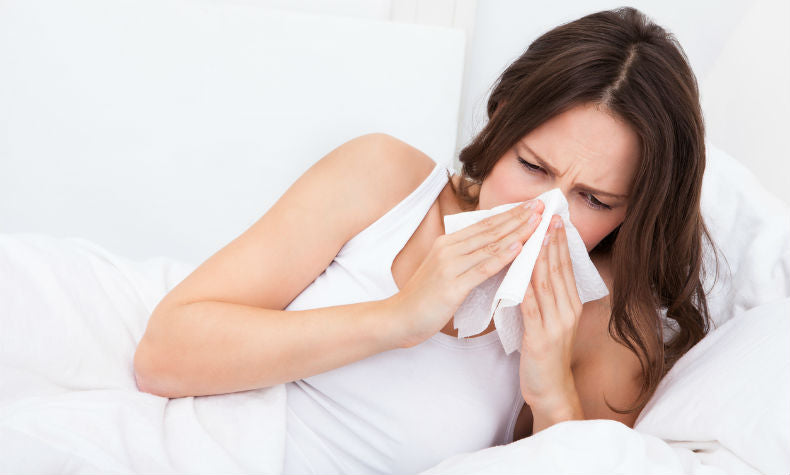 Anti-Allergie-Kissenbezug: Frau liegt im Bett und putzt sich die Nase